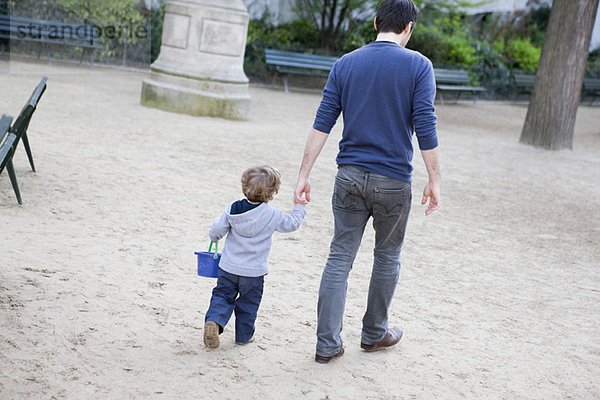 Vater hält die Hand des Kleinkindes Sohnes beim Gehen