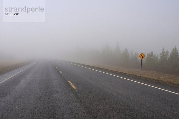 Eine zwei Lane Blacktop Autobahn Streches in die Dunst und Nebel auf einem feuchten Alberta-Morgen