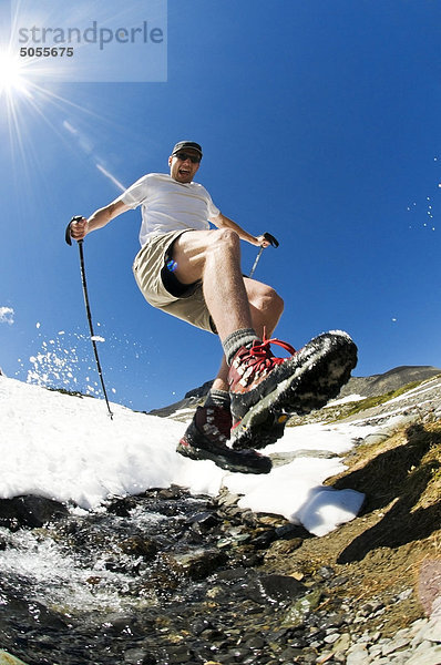 Ein Wanderer springt über einen alpine-Stream über Garibaldi-See im Garibaldi Provincial Park  BC.