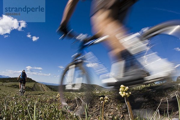 Ein junges paar Mountainbike springen Pfund/Cox Hill in Kananaskis  AB