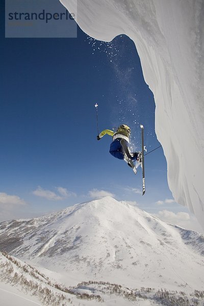 Ein Skifahrer Flys Weg ein Gesims mit Mt Annupuri im Hintergrund  Niseko Backcountry  Hokkaido  Japan