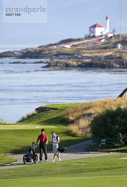 Zwei junge Golfer vergleichen Notizen  spazieren Sie zum nächsten Loch auf Oak Bay Jahrhundert alt  Victoria-Golf-Club in Oak Bay. Victoria  Vancouver Island  British Columbia  Kanada.