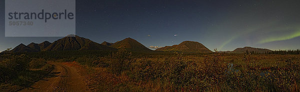 Panoramische Ansicht der mondbeschienene Bergen in der Nähe von Whitehorse mit Aurora und Shooting Stern am Nachthimmel.