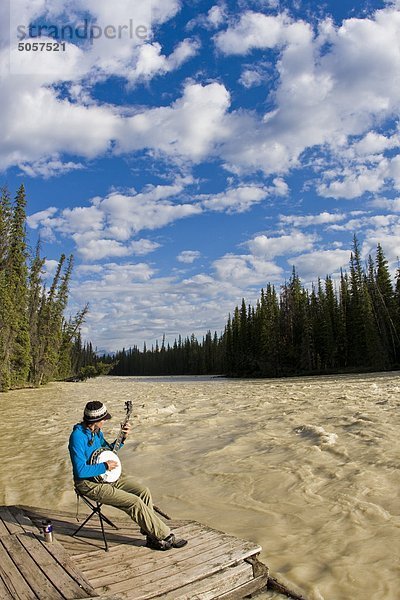 Weibliche Kajakfahrer macht eine Pause vom Paddeln spielen ihre Banjo entlang den Athabasca River  Jasper-Nationalpark in Alberta  Kanada