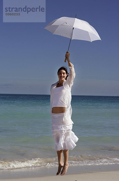 Frau am Strand mit Sonnenschirm