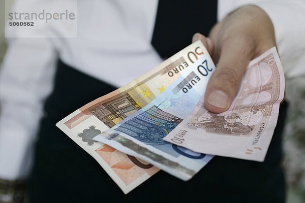 Man's Hand hält Euro-Banknoten