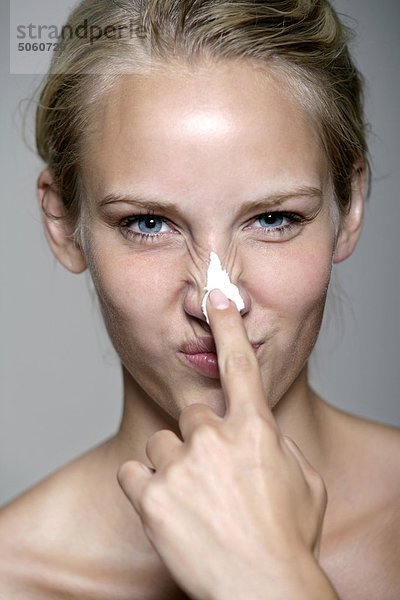Frau Anwendung Creme auf ihre Nase