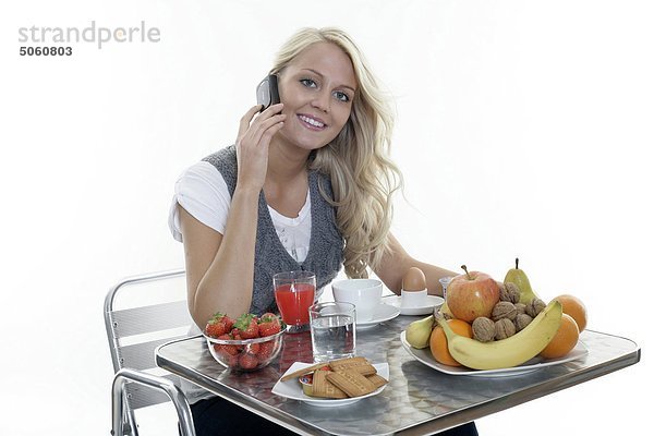 Frau dem Frühstück und Mobiltelefon verwenden