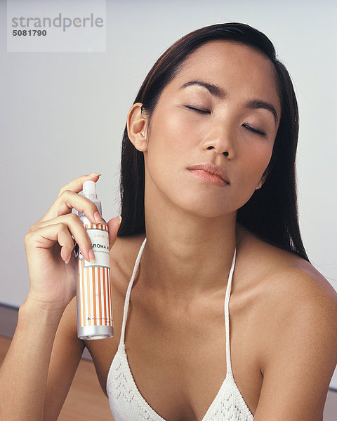 Asiatische Frau mit Flasche Parfüm