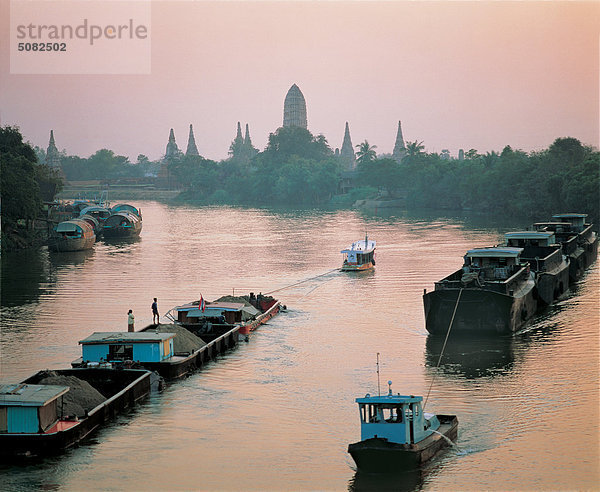 Lastkähne am Fluss Chaophraya in der Dämmerung mit Wat Chai Wattanaram im Hintergrund  Ayutthya  Thailand.