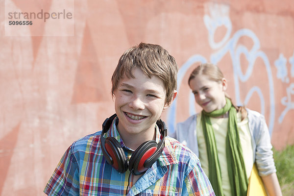Lächelnder Junge mit Kopfhörer und Mädchen mit Mappe
