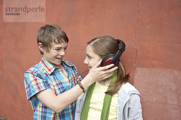 Junge und Mädchen teilen Kopfhörer