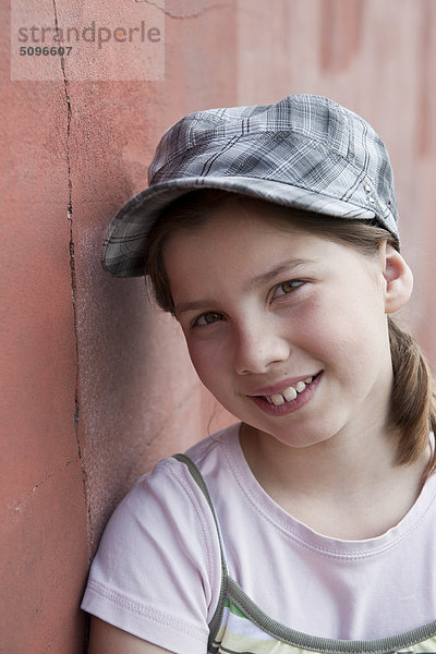 Lächelndes Mädchen lehnt an einer Wand  Portrait