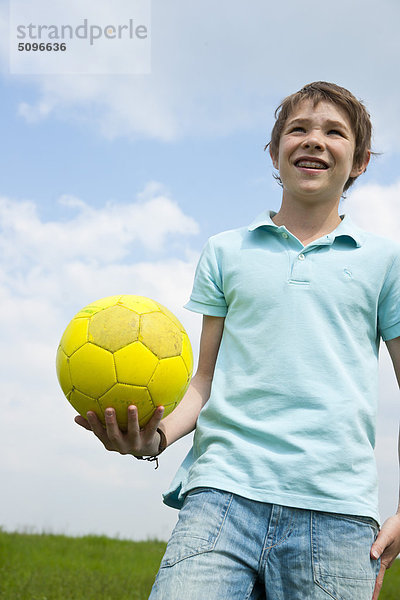 Junge hält einen Fußball im Freien