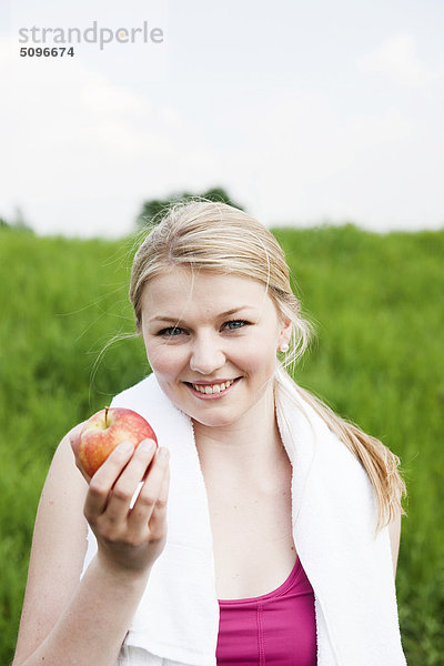 Junge Frau hält eine Apfel im Freien  Portrait