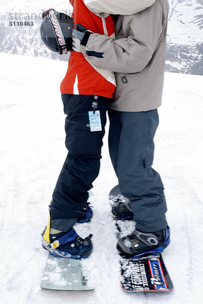 Paar auf Snowboards umarmen
