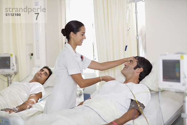Krankenschwester betreut Patientin im Krankenhausbett