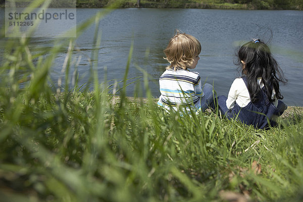 Kinder  die zusammen am Flussufer sitzen