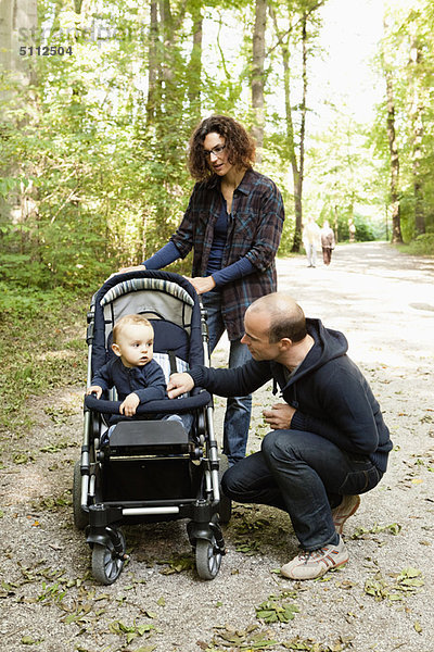 Familie schiebt Baby im Kinderwagen