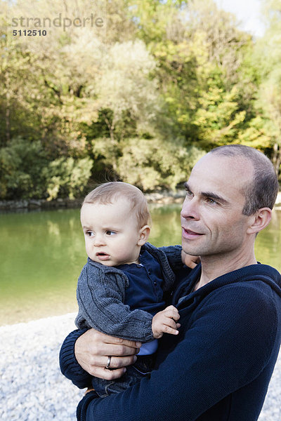 Vater hält Baby am Bach