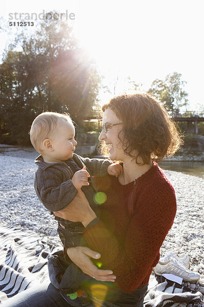 Mutter hält Baby am Bach