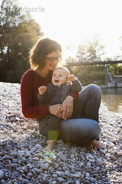 Mutter hält Baby am Bach