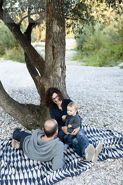 Familie entspannt sich gemeinsam unter einem Baum
