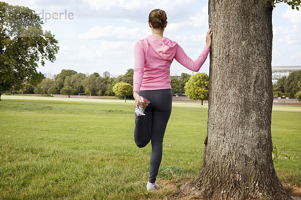 Frau streckt sich im Park