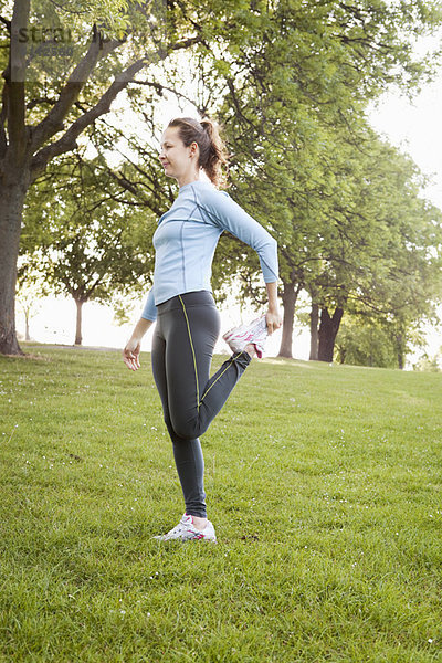 Frau streckt sich im Park