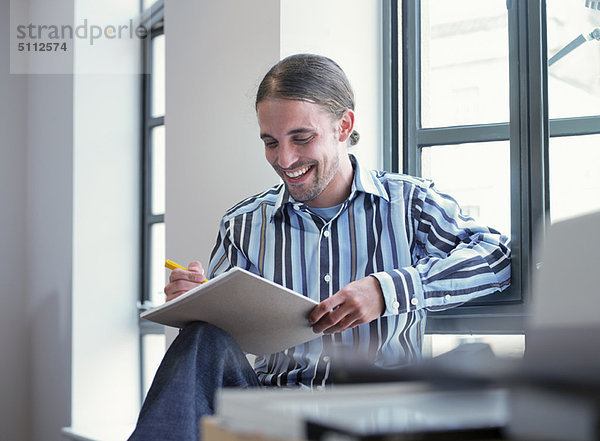 Lächelnder Geschäftsmann beim Schreiben im Büro