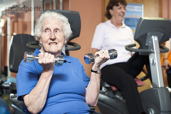Ältere Frau beim Heben von Gewichten im Fitnessstudio