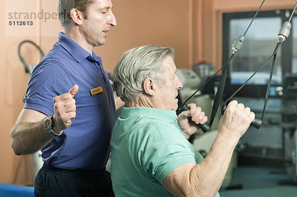 Trainer hilft älteren Männern beim Training