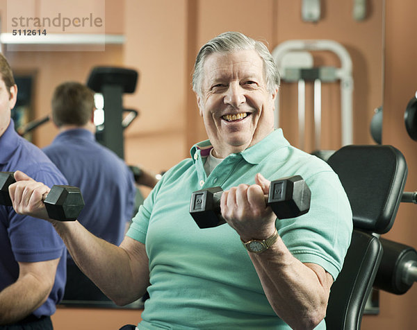 Älterer Mann beim Heben von Gewichten im Fitnessstudio