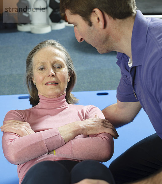 Trainerin hilft älteren Frauen beim Training