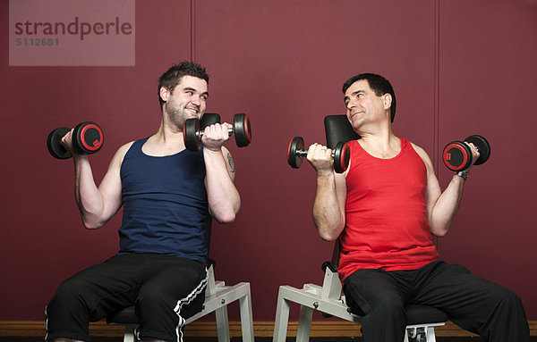 Männer  die gemeinsam in der Turnhalle Gewichte heben