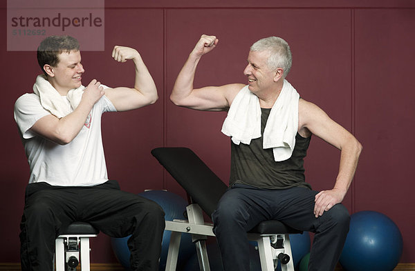 Vater und Sohn beugen Muskeln in der Turnhalle