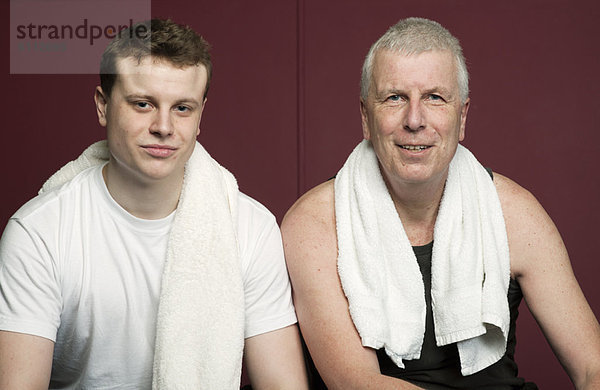Vater und Sohn mit Handtüchern im Fitnessstudio