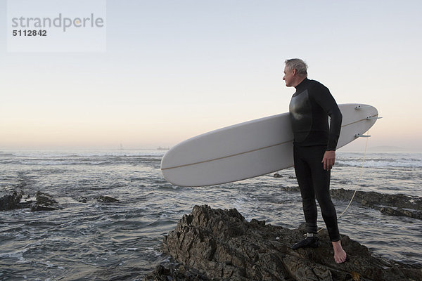 Surfer am Felsstrand stehend