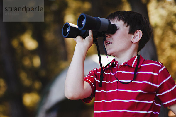 Junge mit Fernglas auf dem Campingplatz