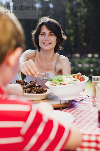 Mutter serviert Salat beim Picknick