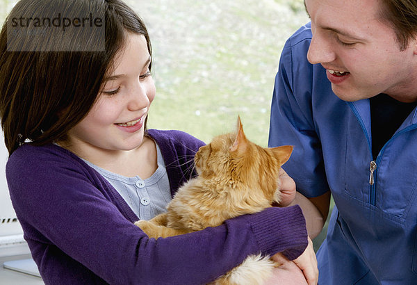 Tierarzt im Gespräch mit einem Mädchen mit ihrer Katze