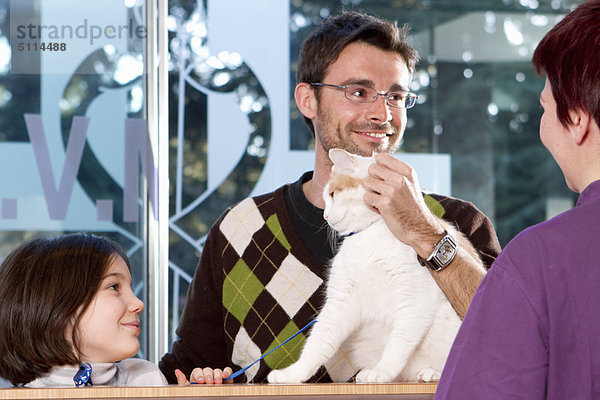 Mann mit Tochter und Katze beim Tierarzt