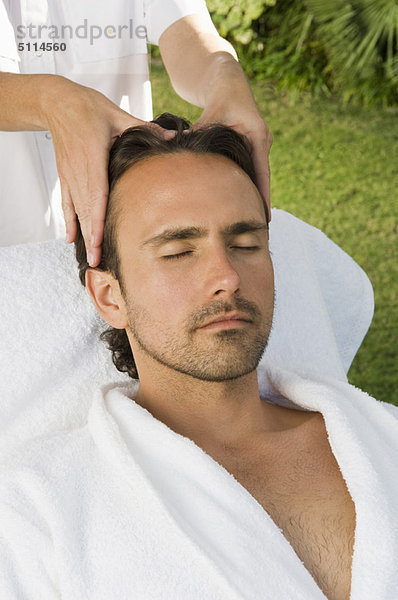 Mann mit Kopfhautmassage im Freien