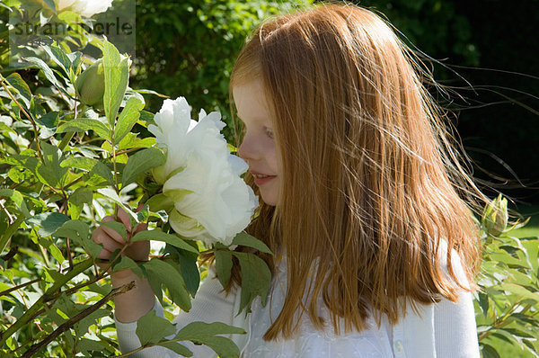 Mädchen riecht Blumen im Garten