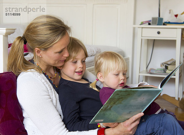 Mutter liest den Kindern im Schlafzimmer vor