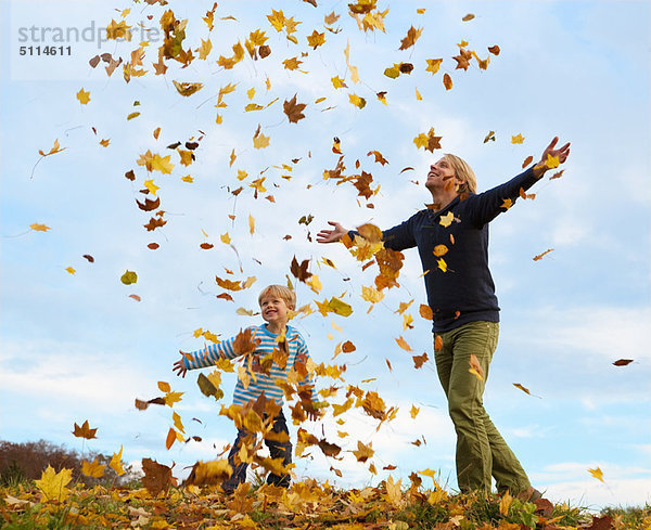 Vater und Sohn spielen im Herbstlaub