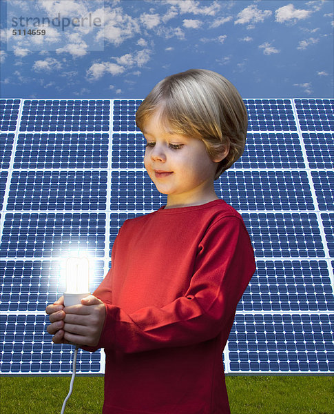 Junge mit Glühbirne durch Solarmodul