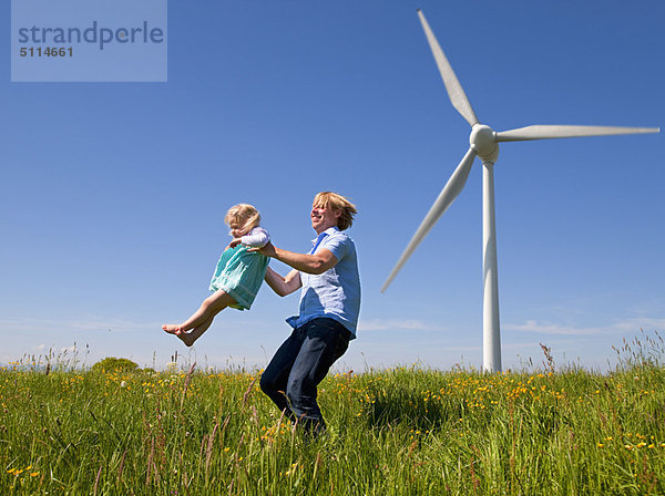 Mann in der Tochter im Feld durch Windkraftanlage