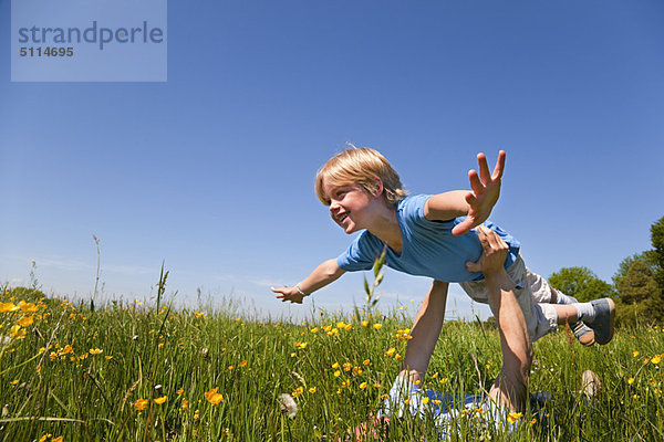 Vater und Sohn spielen Flugzeug im Feld