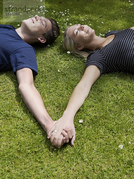 Paar hält Hände im Gras